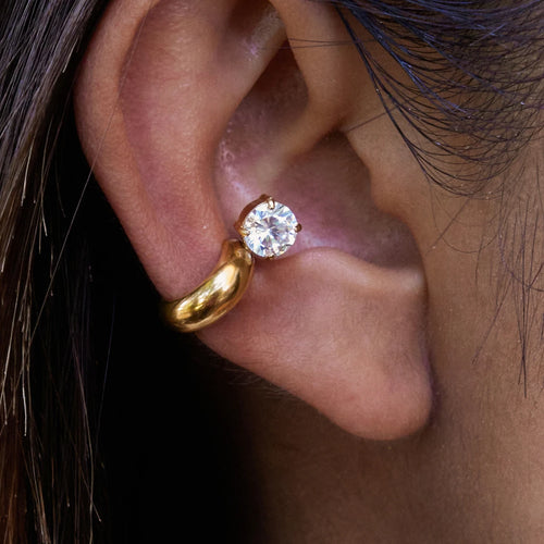 Gold earring with a diamond on an ear